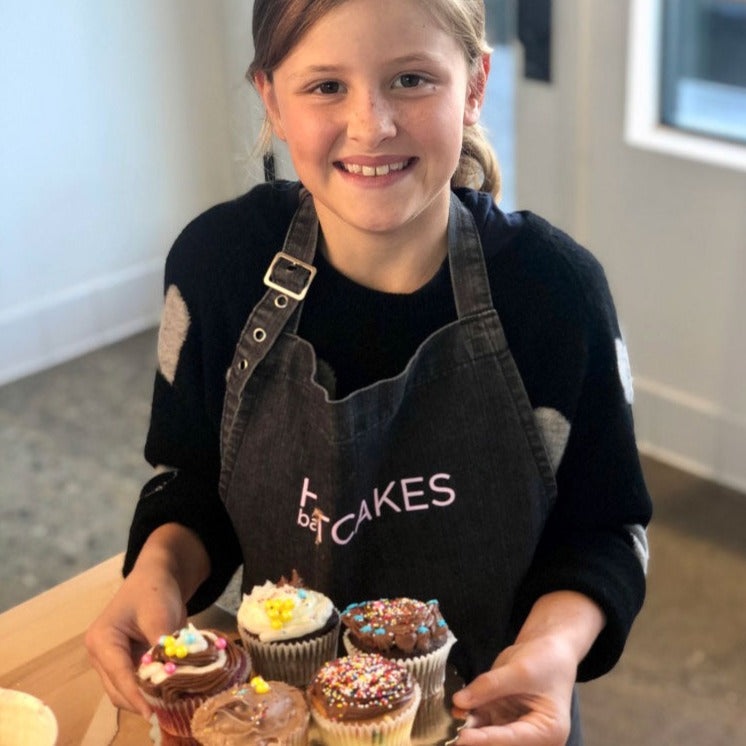 girl holding cupcakes and smiling